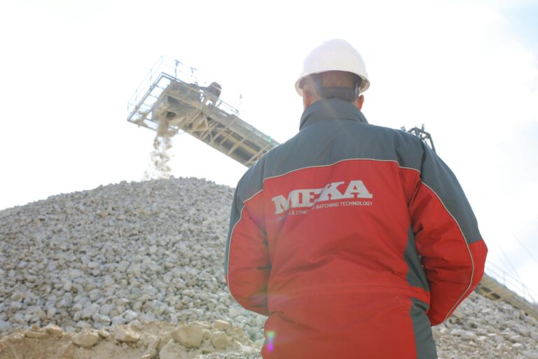 Back view of a construction worker in Ankara quarry observing a conveyor belt at a gravel site.