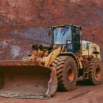 Large yellow bulldozer operating in a mining quarry with rugged terrain.