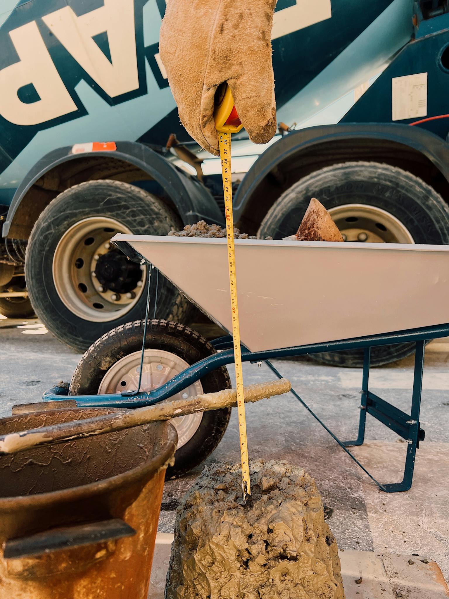 Worker measures cement mix consistency with tape measure at construction site.
